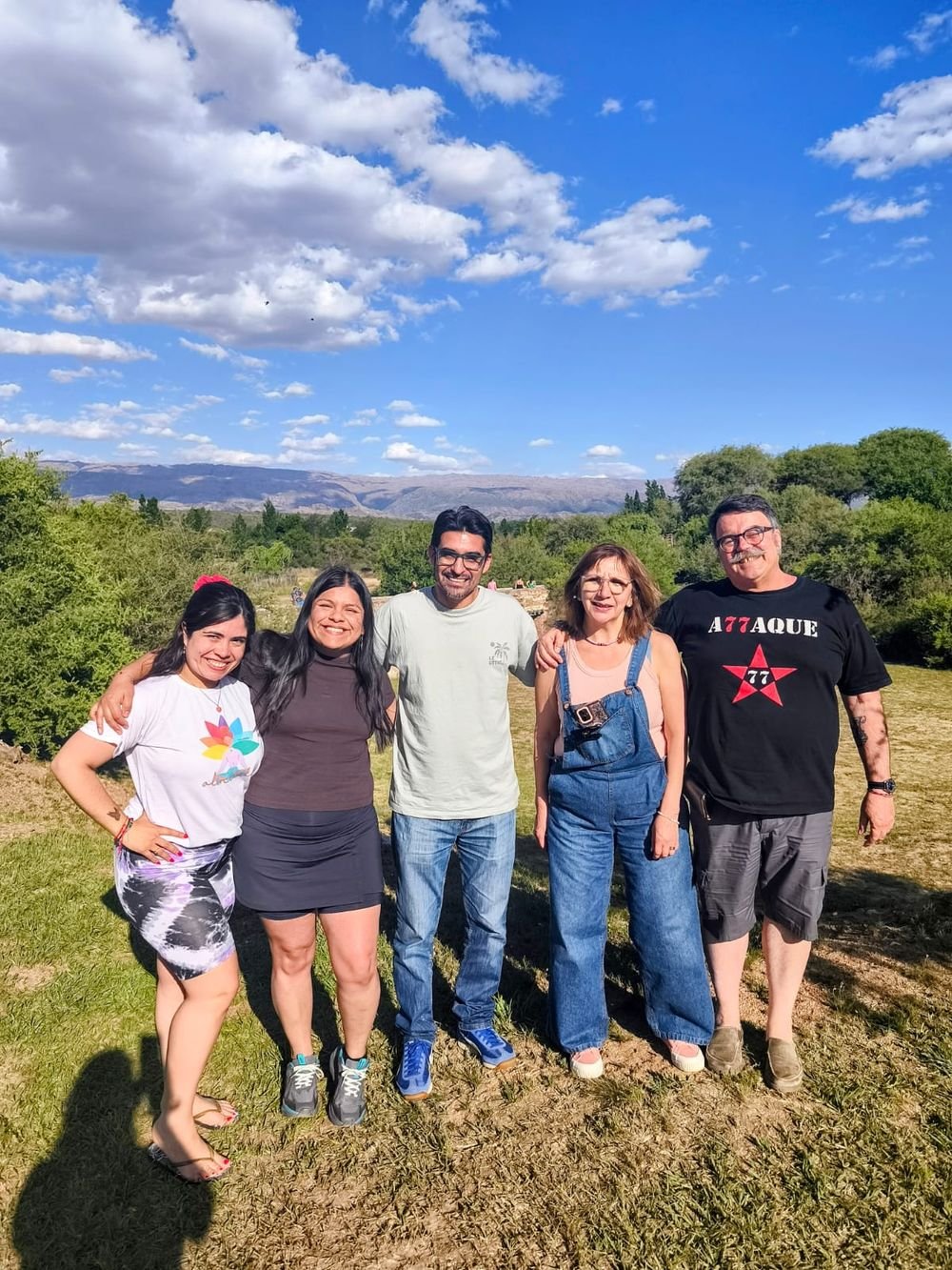 Cinco participantes abrazados en un parque con las sierras detrás.